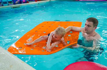 A man is holding a baby on a pool float