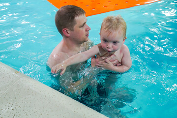 A man is holding a child in a pool