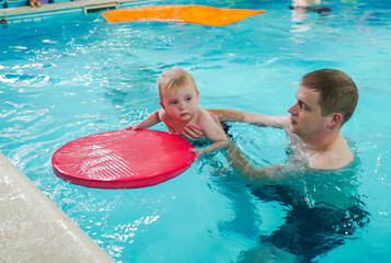 A man is holding a baby in a pool