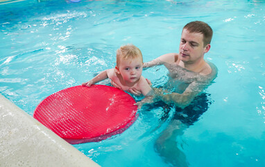A man is holding a baby in a pool