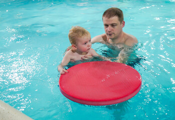 A man is holding a baby in a pool