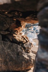 Scenic view of the traditional whitewashed village of Chora on the Greek island of Amorgos, seen through the opening of an old stone wall or ruins. 