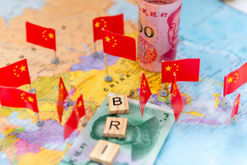 Letter tiles, Chinese Yuan bank notes and national flags on a word map. A Belt And Road Initiative concept.