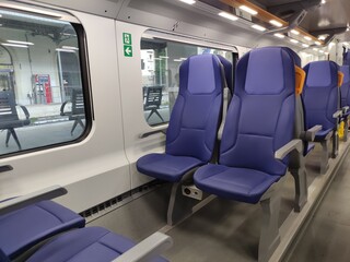 Modern train interior featuring spacious blue seats with ergonomic design, showcasing a clean and...