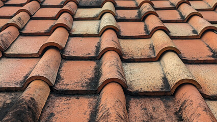 Clay tiles. Close-up photo of a clay tile roof against a blue sky background. Old and dirty clay...