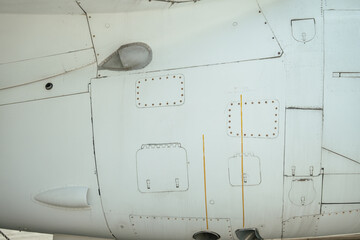 Detailed view of a military aircraft exterior featuring panels, access hatches, and rivets. Visible...