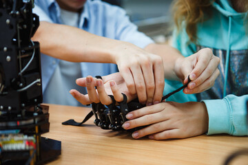 Students assembling robotic glove during STEM class, focusing on collaboration and hands-on...