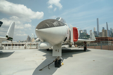 A jet fighter aircraft is displayed on a rooftop deck with tall city buildings in the background....
