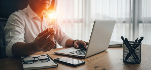 Light bulb in male hand, online technology inspiration, man using notebook computer, creative innovation concept.