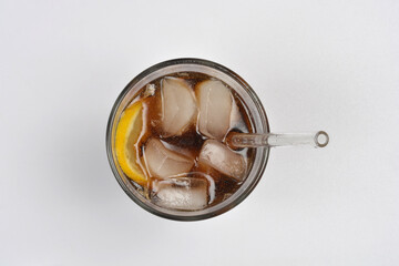 A top-down view shows a glass of dark soda filled with ice and a lemon slice, featuring a straw, on a white background