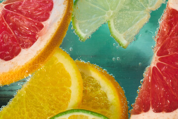 Bright slices of grapefruit, lime, lemon, and orange are immersed in sparkling water, creating a...