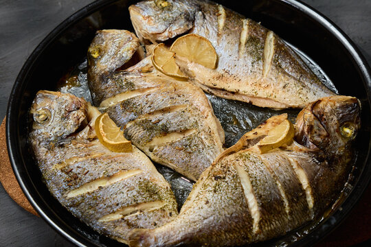 Freshly grilled dorado fish served on a platter with lemon slices and salt for a delicious seafood meal