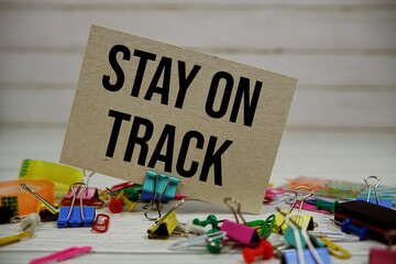 Stay On Track text on paper card with stationary on wooden background