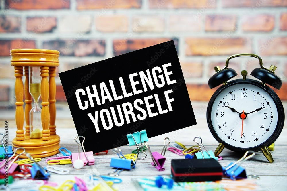 Poster challenge yourself text on paper card with alarm clock and stationary on wooden background