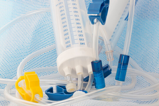 Close-up of pediatric peritoneal dialysis system with burette, bag connectors, and catheters to bridge the time until transplantation on medical gaze covering blue background