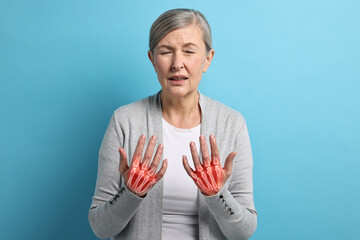 Arthritis. Senior woman suffering from pain in hands on light blue background. Illustration of...