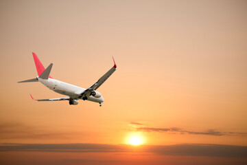 Airplane flying in beautiful sky with clouds at sunset