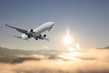 Airplane flying above mountains in beautiful sky on sunny morning