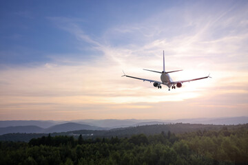 Airplane flying above mountains in beautiful sky at sunrise
