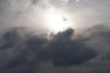 Obraz premium A sky with a bright sun, partially obscured by dark clouds