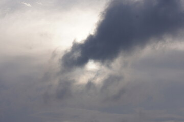 The sky filled with dark, heavy clouds, with a brighter area suggesting a break in the cloud cover or a hidden sun