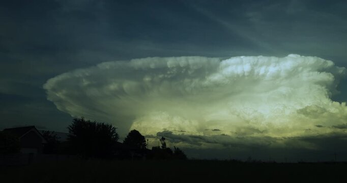 Timelapse of wide angle dramatic view of a massive growing supercell cloud formed in the blue sky prepaparing for a thunder storm
