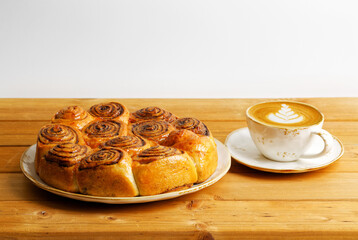 Homemade cinnamon rolls from yeast dough and cup of coffee cappuccino on wooden table. Copyspace.