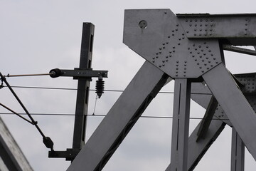 A close-up view of a metal structure, a part of a bridge , alongside elements of an electrical transmission system