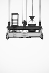 Cables and couplings of a container crane, suspended in the air. In black and white.