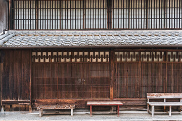 Rustic exterior of Japanese Machiya facade house with brown wooden sliding door, lattice design and benches