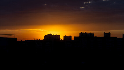Orange sky. Morning in town. Panorama of the metropolis. Silhouette of houses. Peaceful life. Calm sky. Color gradient in nature. Heavenly landscape. Urban skyline.