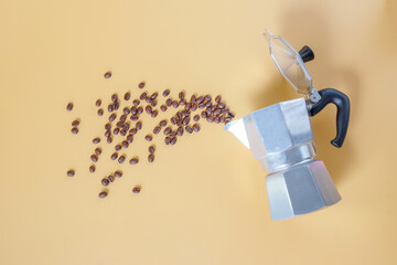 top view of aluminium moka pot and scattered fresh coffee beans.