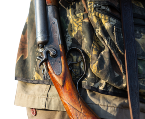 Mature man hunter with gun while walking on field.
