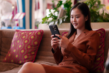 Empowered Asian business woman confidently uses smartphone for digital communication networking and...