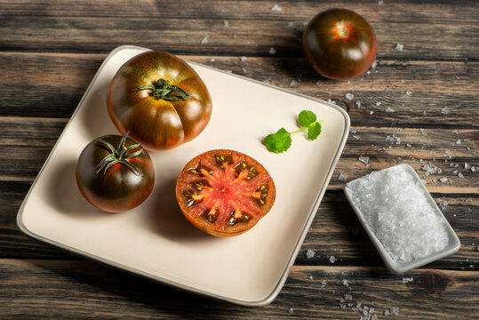 Otello tomato, a sweet and flavorful hybrid, halved with flaky salt on a plate, top-down view.