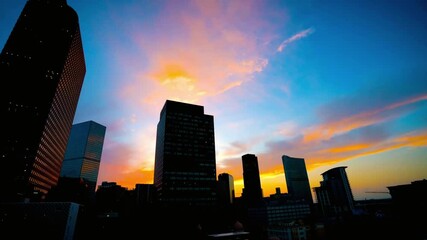 The city skyline is silhouetted against a vibrant sunset sky