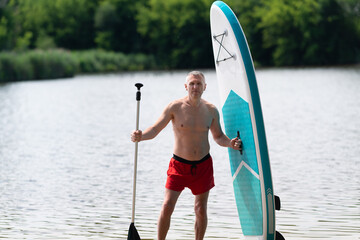 A man stands with a paddle and a SUP board.