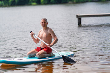 A man on a SUP board floats across a lake.