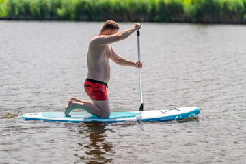 Using a SUP board, a young man is using it.