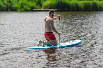 A person in their early 30s is using a SUP board.