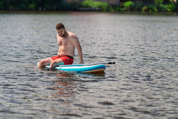A man relaxed on a SUP board in the middle of a lake.