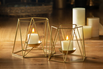 Elegant glass candle holders, softly glowing with warm candlelight, stand on a wooden surface...