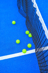 vibrant blue court with a black net and numerous bright green balls