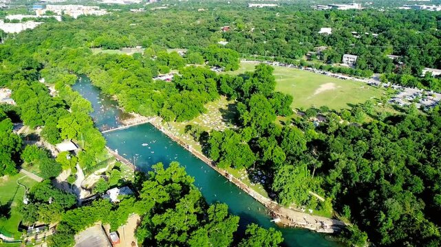 Aerial view of barton springs pool surrounded by lush green trees