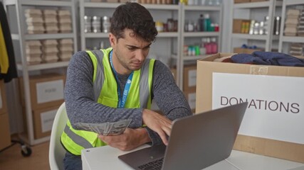 Man held cash while counting records in a warehouse by a hispanic volunteer beside a donation box near a laptop tracking money. - Powered by Adobe
