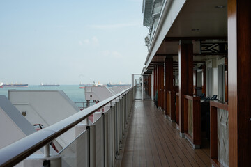 cruise ship deck overlooking ocean with distant ships under blue sky