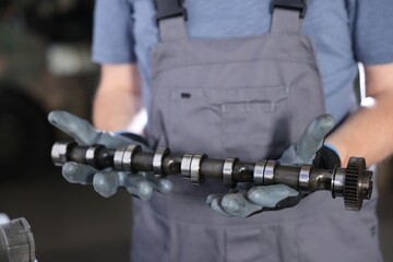 Auto part. Professional mechanic with camshaft indoors, closeup view