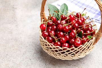 Wet ripe cherries in basket on light table, closeup. Space for text
