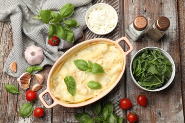 Tasty vegetarian lasagna and ingredients on wooden table, flat lay