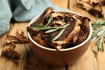 Dried chanterelle mushrooms with rosemary on wooden table, closeup